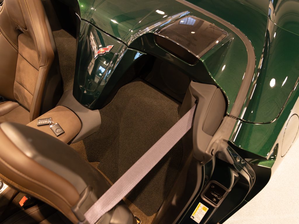 Interior view of a green car showing brown leather seats and a seatbelt. - Monarch Showroom