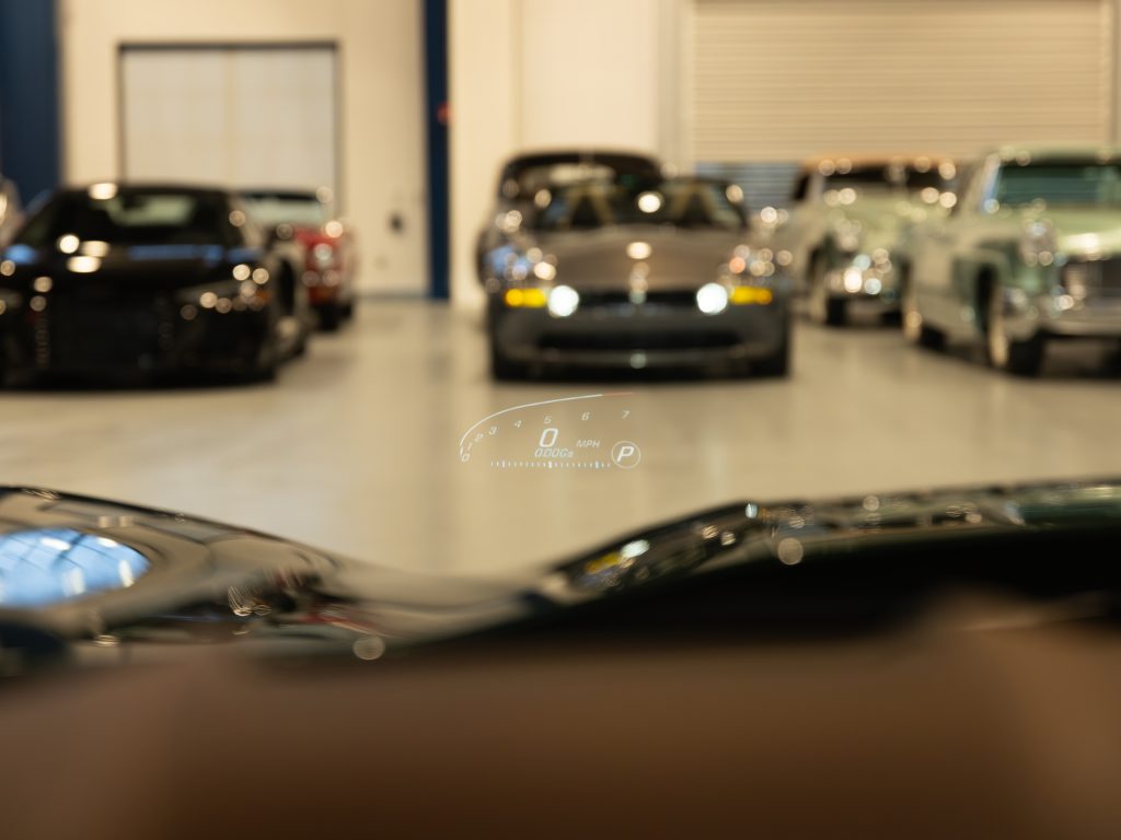 Luxury cars parked in a showroom, viewed from behind the steering wheel of a car with a digital dashboard display. - Monarch Showroom