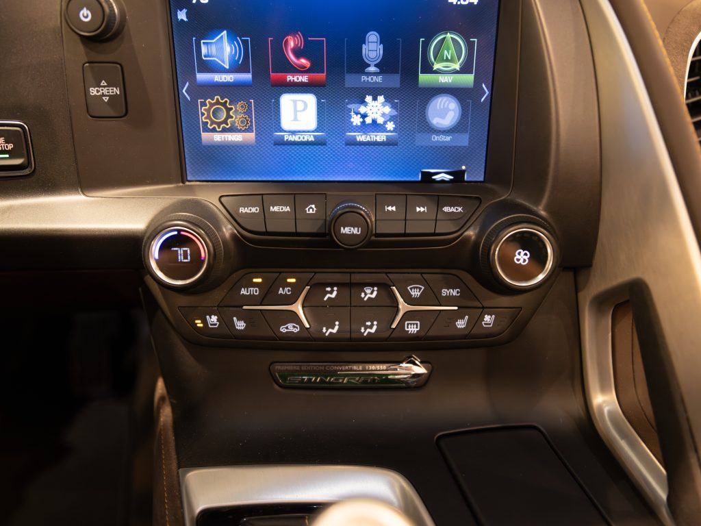 Interior view of a vehicle's center console featuring an infotainment touchscreen display and climate control buttons. - Monarch Showroom