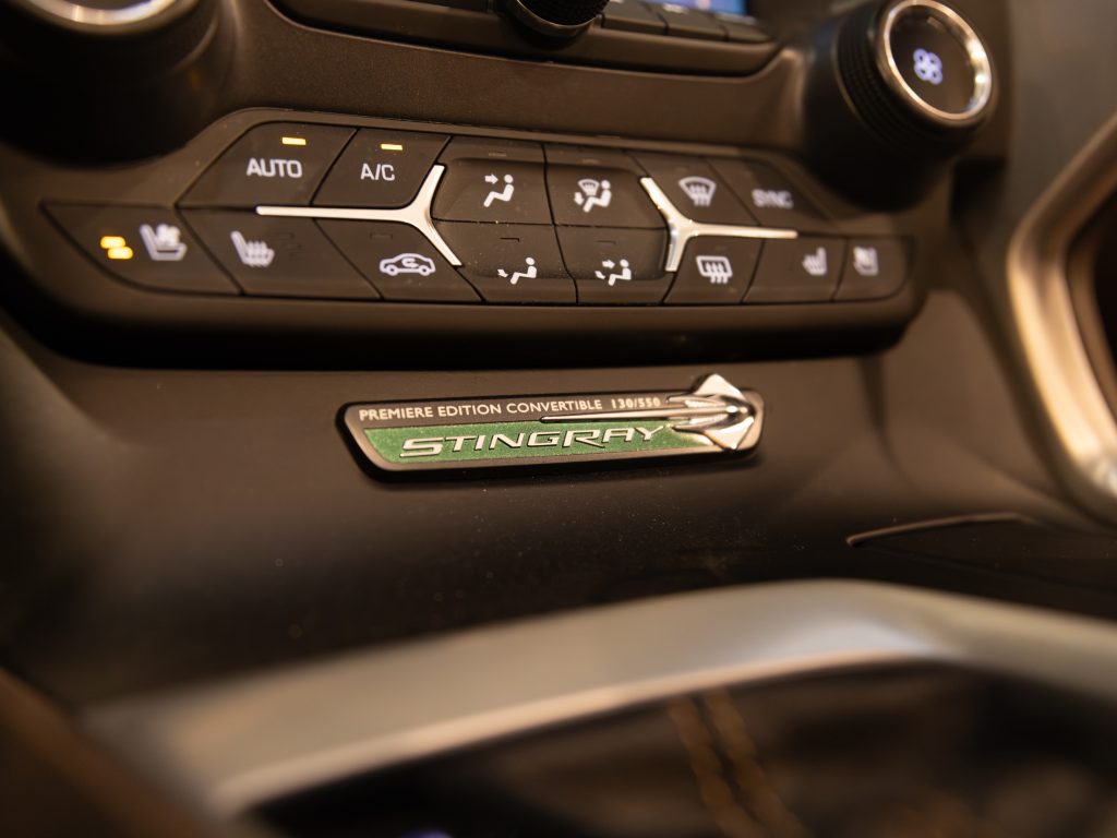 Interior close-up of a vehicle's climate control panel and a 'premiere edition convertible stingray' badge. - Monarch Showroom