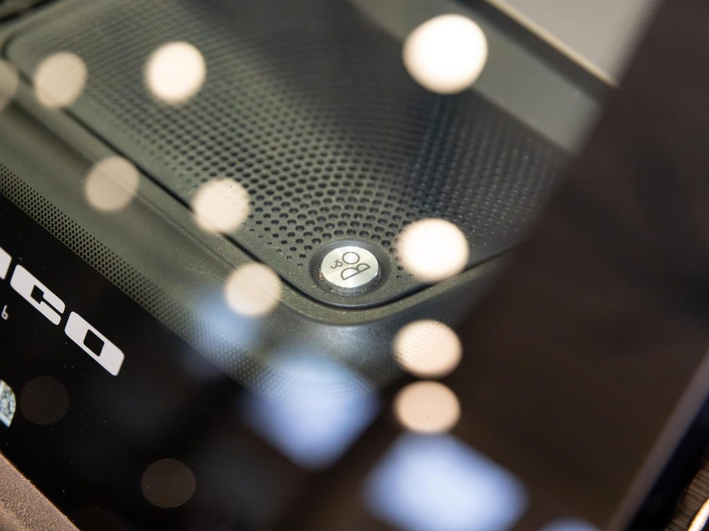 Close-up of an electronic device with a glossy surface and speaker grille, featuring a logo with two overlapping circles and a letter 'b'. - Monarch Showroom