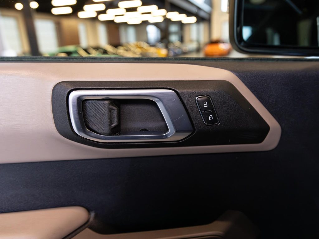 Car door interior with window control buttons and door handle. - Monarch Showroom