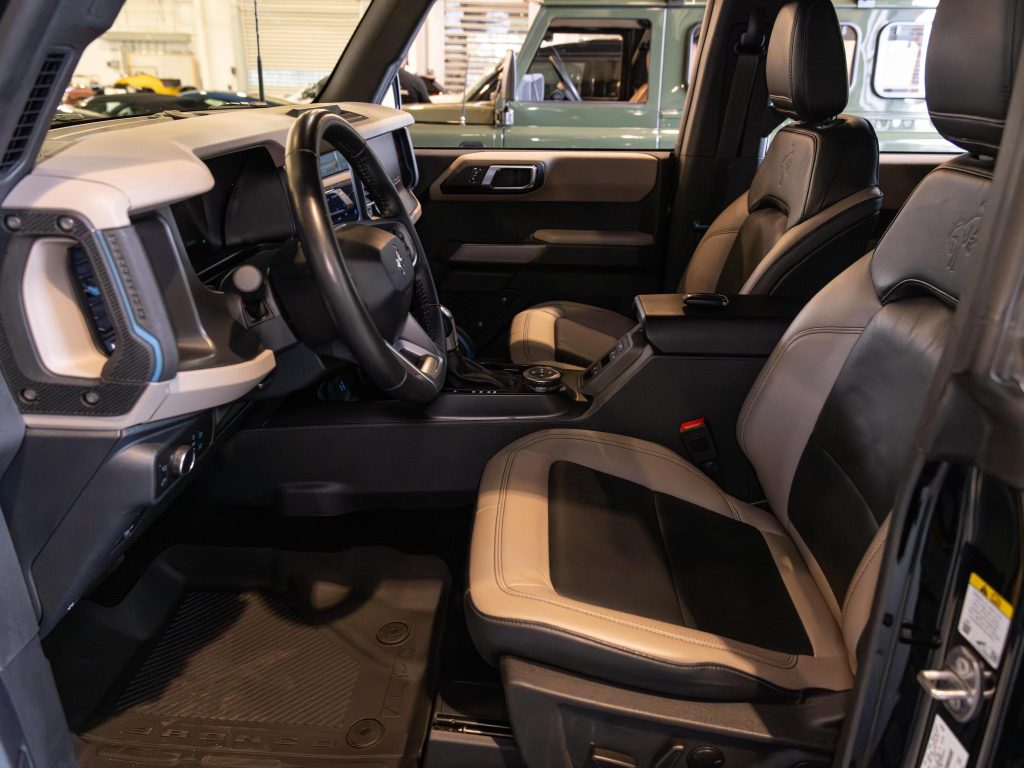 Interior view of a modern vehicle showcasing the driver's seat, steering wheel, center console, and dashboard. - Monarch Showroom