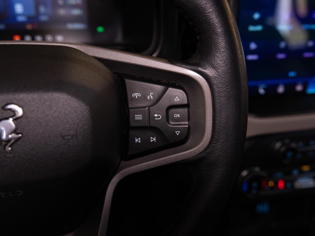 Close-up of a car's steering wheel controls with multimedia and information functions. - Monarch Showroom
