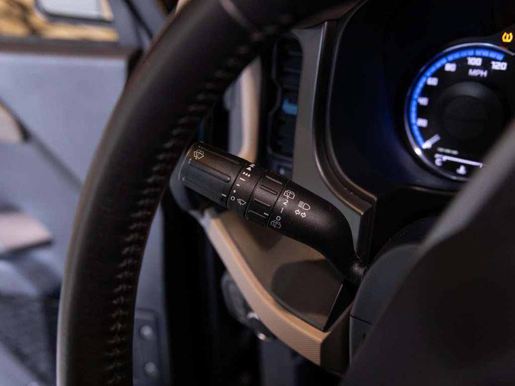 Close-up of a vehicle's steering wheel and turn signal lever with indicator and wiper controls. - Monarch Showroom