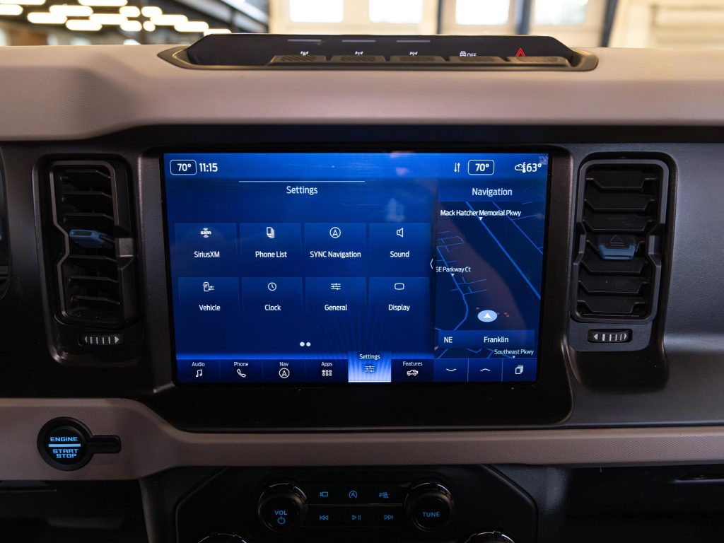 In-vehicle infotainment system displaying navigation and settings menu on a touchscreen. - Monarch Showroom