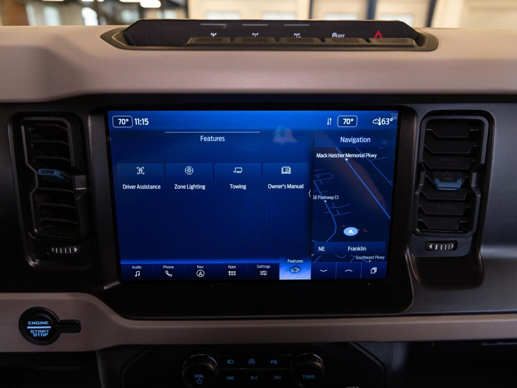 In-vehicle infotainment system displaying a navigation map and various features like driver assistance, zone lighting, and towing options. - Monarch Showroom