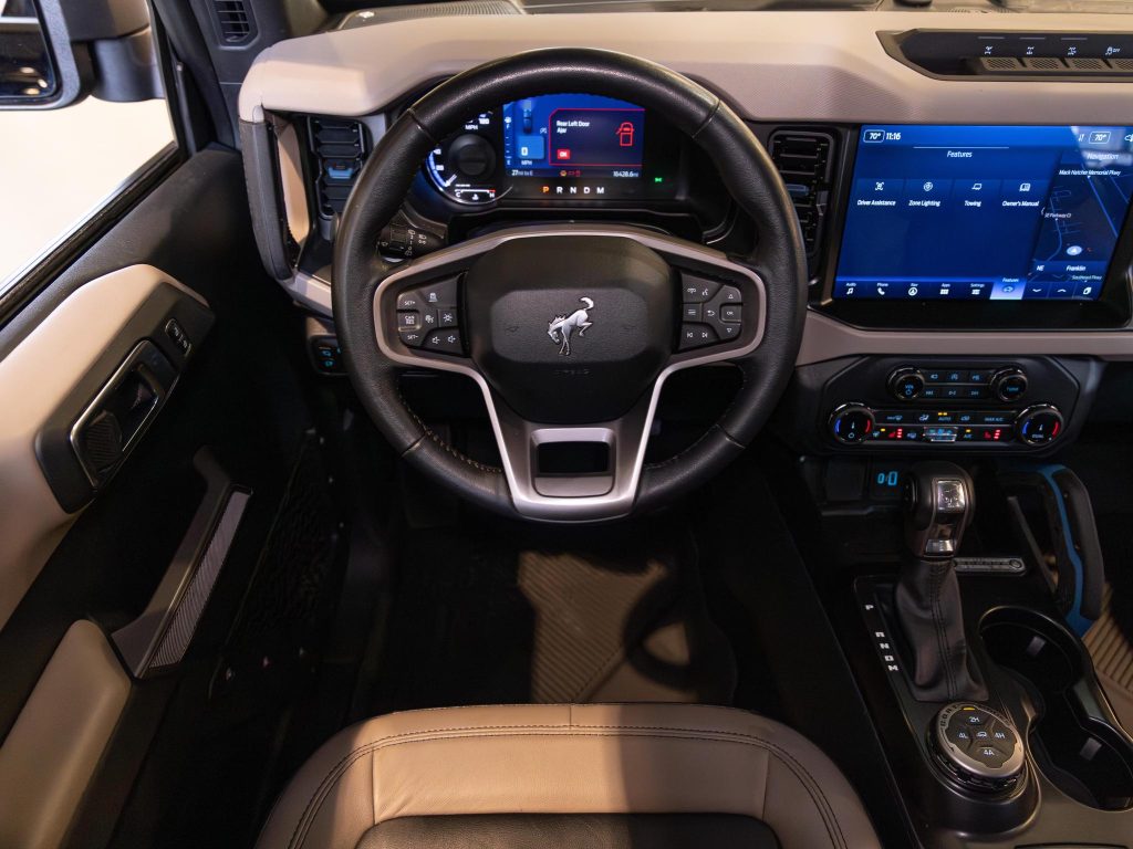 Modern vehicle dashboard and steering wheel with digital displays and infotainment system. - Monarch Showroom