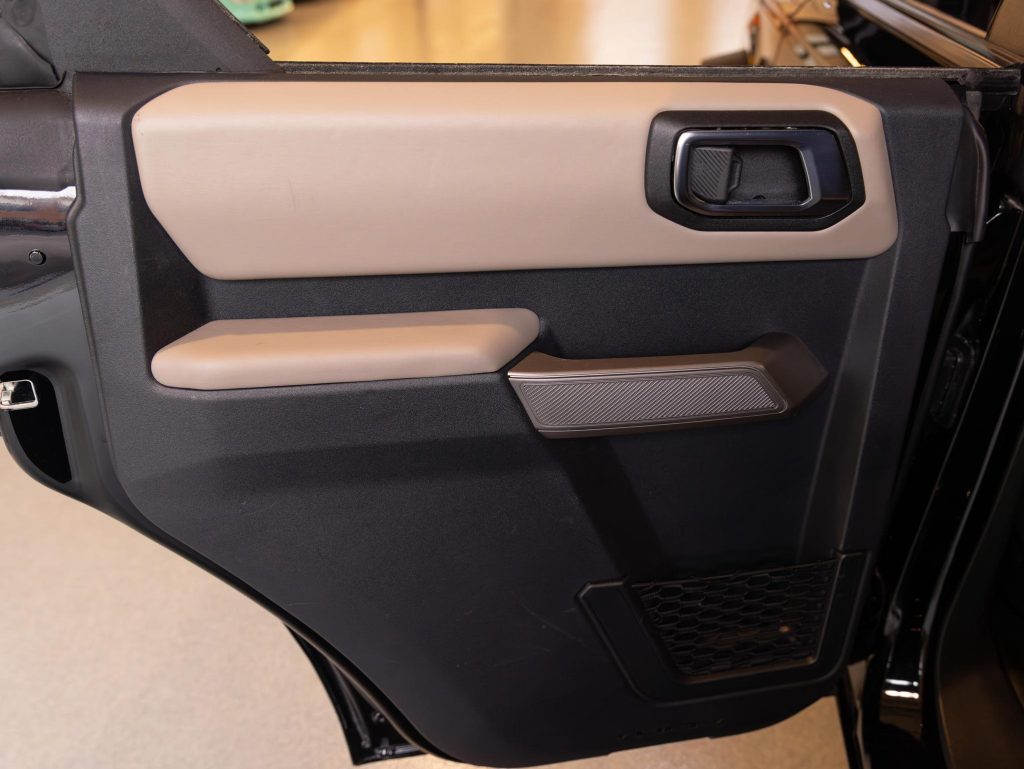 Interior door panel of a vehicle with handle, control buttons, and storage compartment. - Monarch Showroom