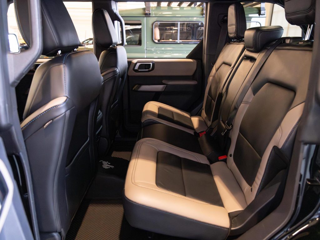 Interior view of a vehicle showcasing its black leather rear seats with a fold-down center armrest. - Monarch Showroom