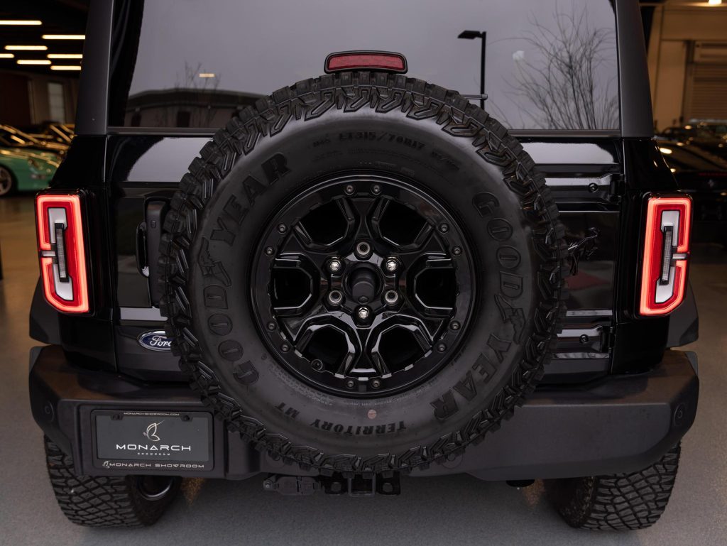 Rear view of a black suv with a spare tire mounted on the back. - Monarch Showroom