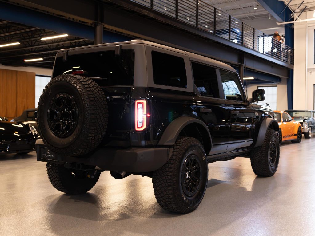 Black suv parked in an indoor showroom with other vehicles in the background. - Monarch Showroom