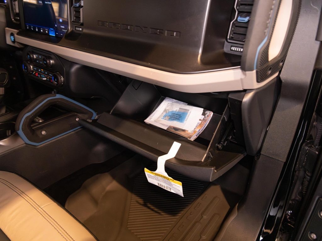 Interior view of a vehicle's passenger side showing an open glove compartment with a manual inside and a clean, organized cabin. - Monarch Showroom