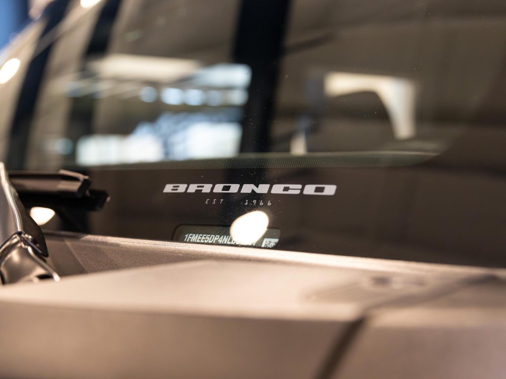 Close-up of a "bronco" logo on a vehicle dashboard, with a blurred background. - Monarch Showroom