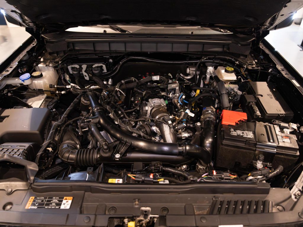 A close-up view of a modern car's open engine bay, revealing a complex array of components and assemblies. - Monarch Showroom