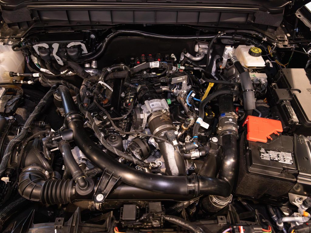 Close-up view of a modern car engine compartment with various components and wiring visible. - Monarch Showroom
