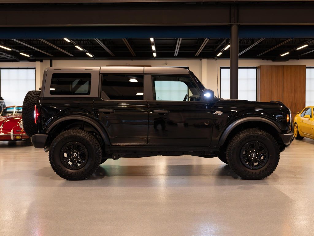 Black suv parked indoors with other vehicles in the background. - Monarch Showroom