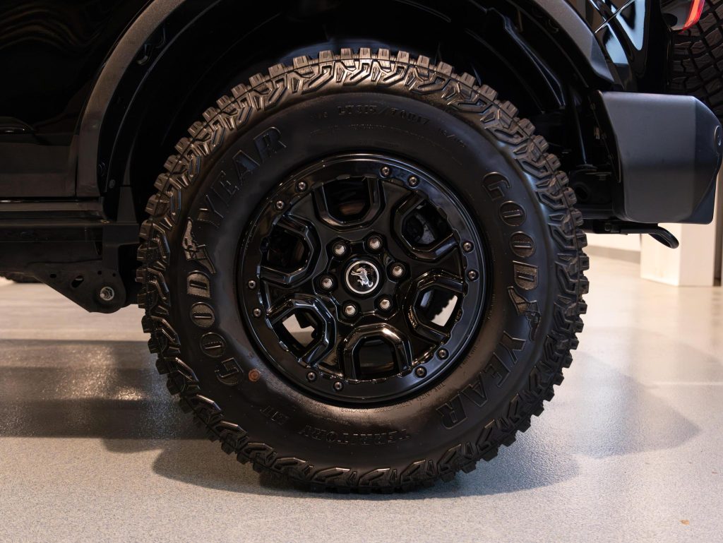 Close-up view of an off-road vehicle's black alloy wheel with an all-terrain tire. - Monarch Showroom