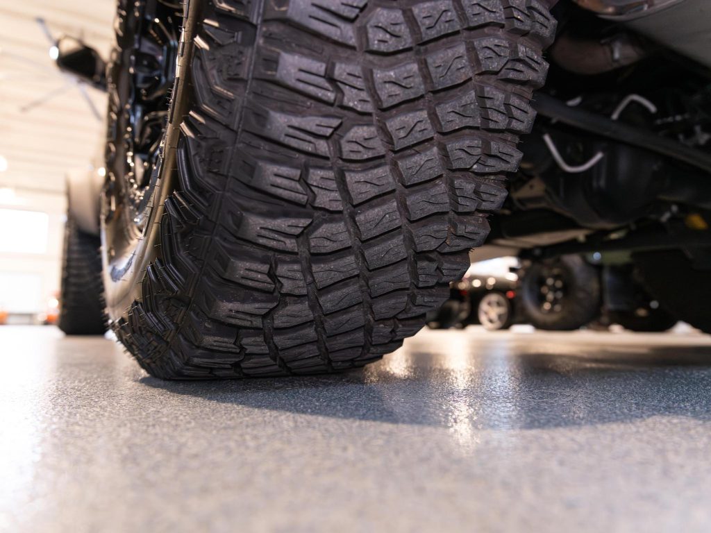 Close-up of a vehicle's tire tread pattern with other vehicles in background. - Monarch Showroom