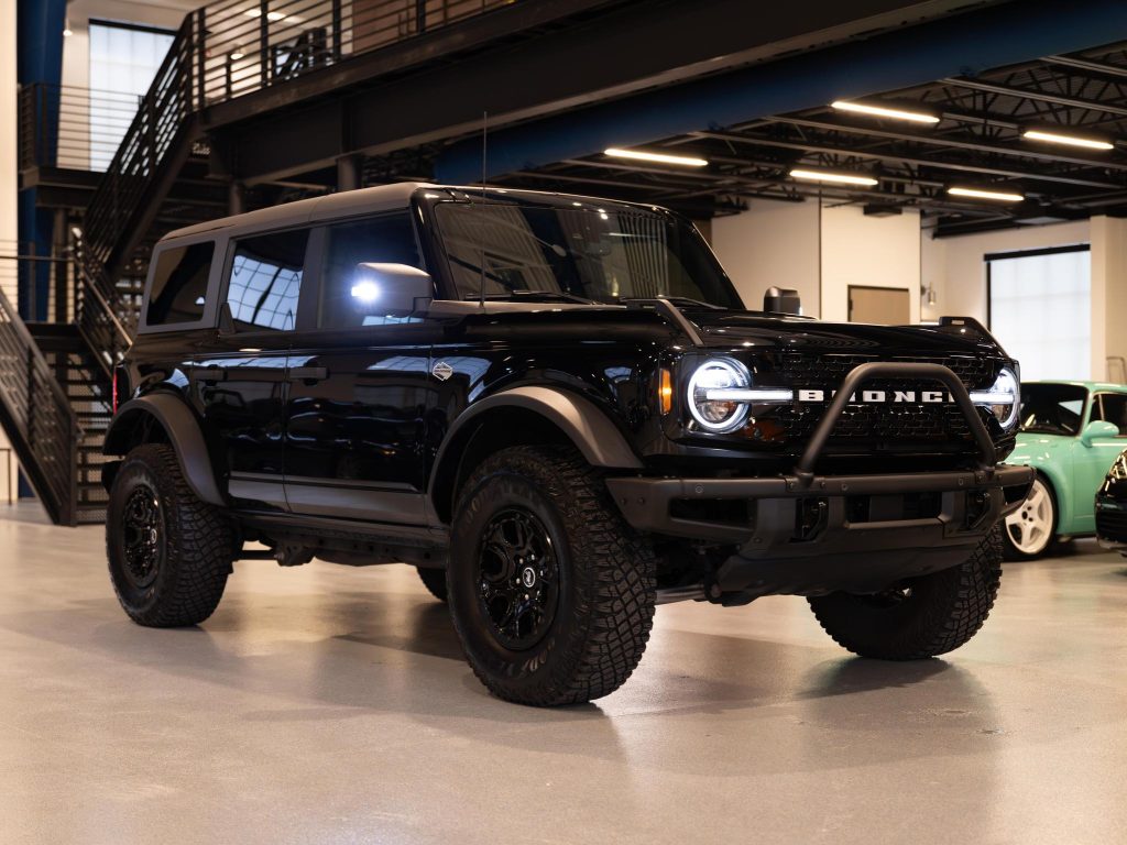 A black ford bronco parked indoors with a shiny finish and rugged tires. - Monarch Showroom