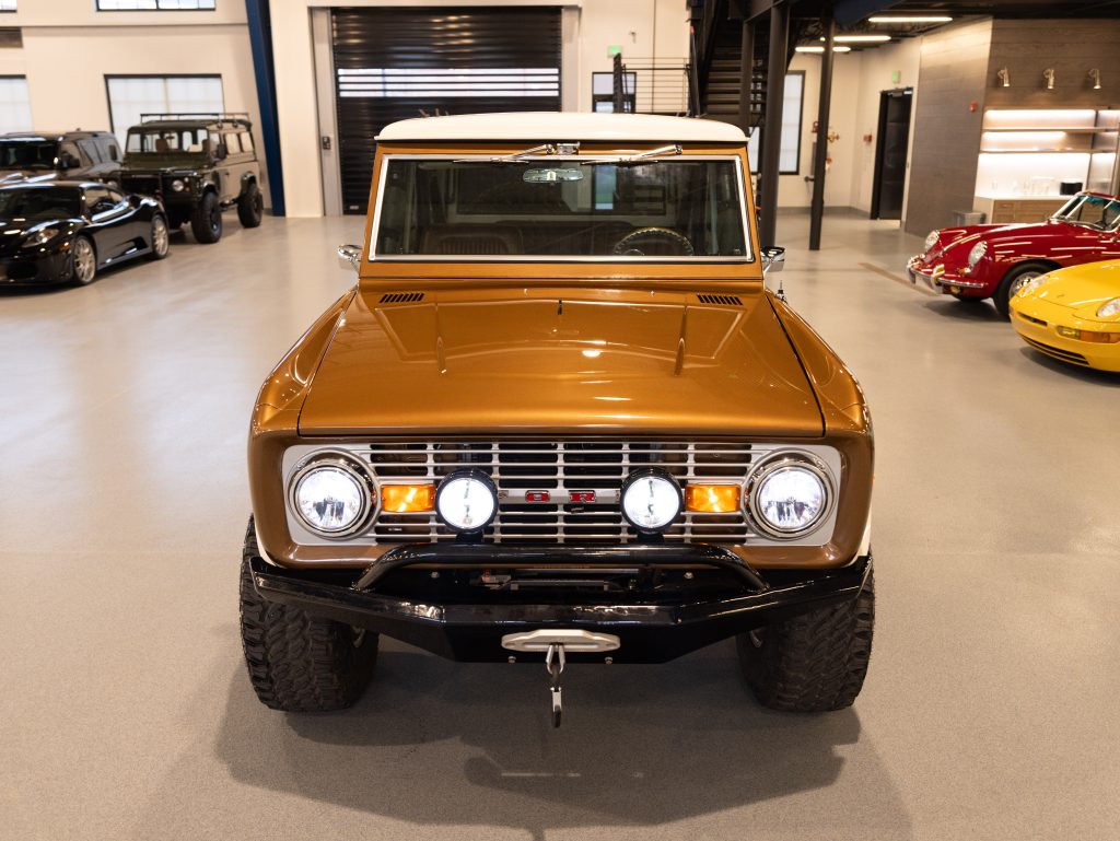 Vintage brown suv with auxiliary lights, displayed in a showroom between classic cars. - Monarch Showroom