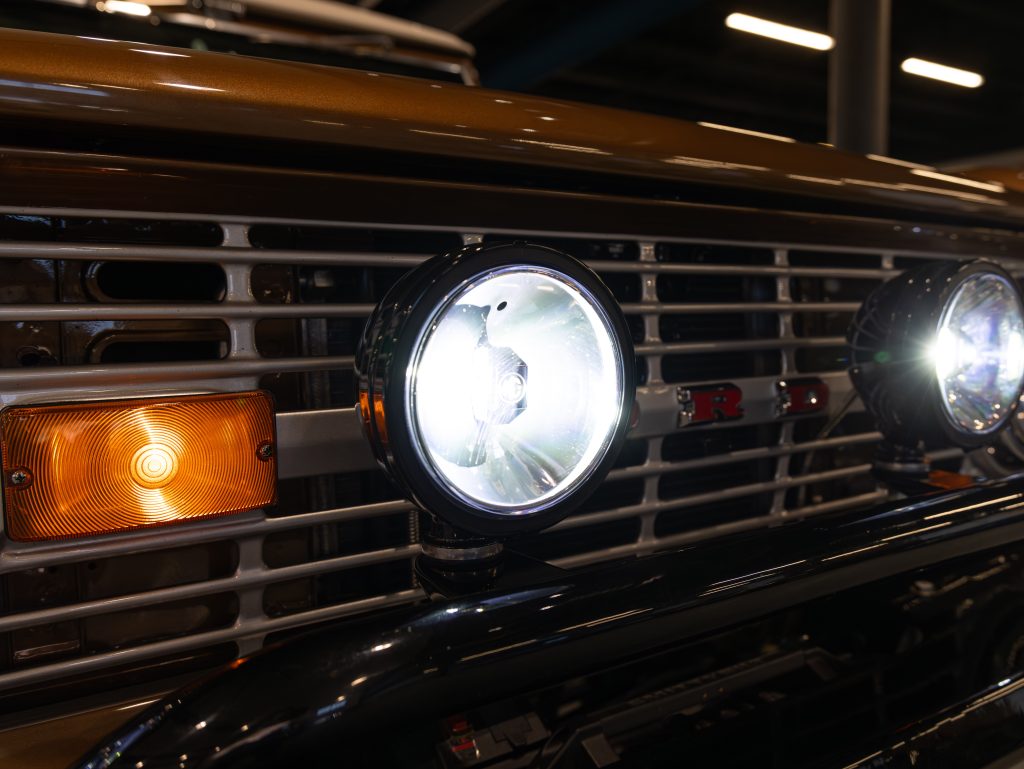 Close-up of a vintage car's grille and illuminated headlights. - Monarch Showroom