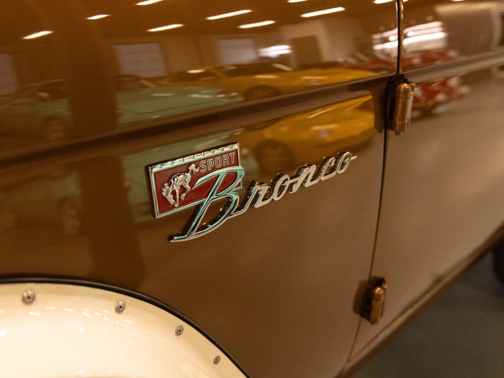 Close-up of a ford bronco emblem on a vintage vehicle with reflections of other cars in the background. - Monarch Showroom