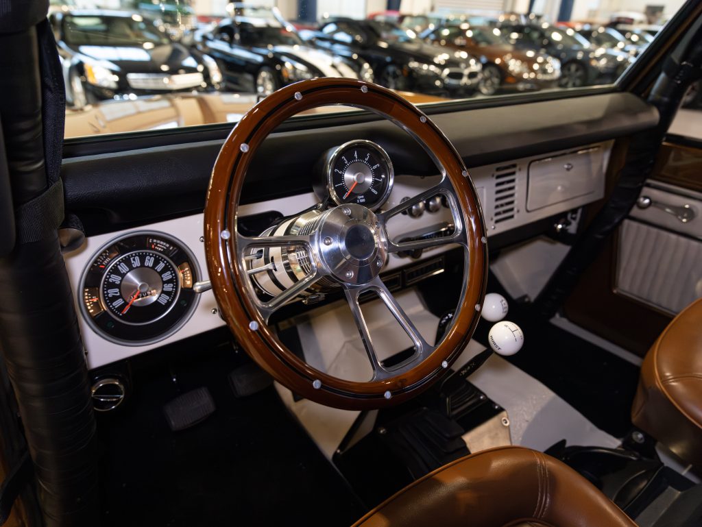 Interior of a classic car showcasing a wooden steering wheel and vintage dashboard. - Monarch Showroom