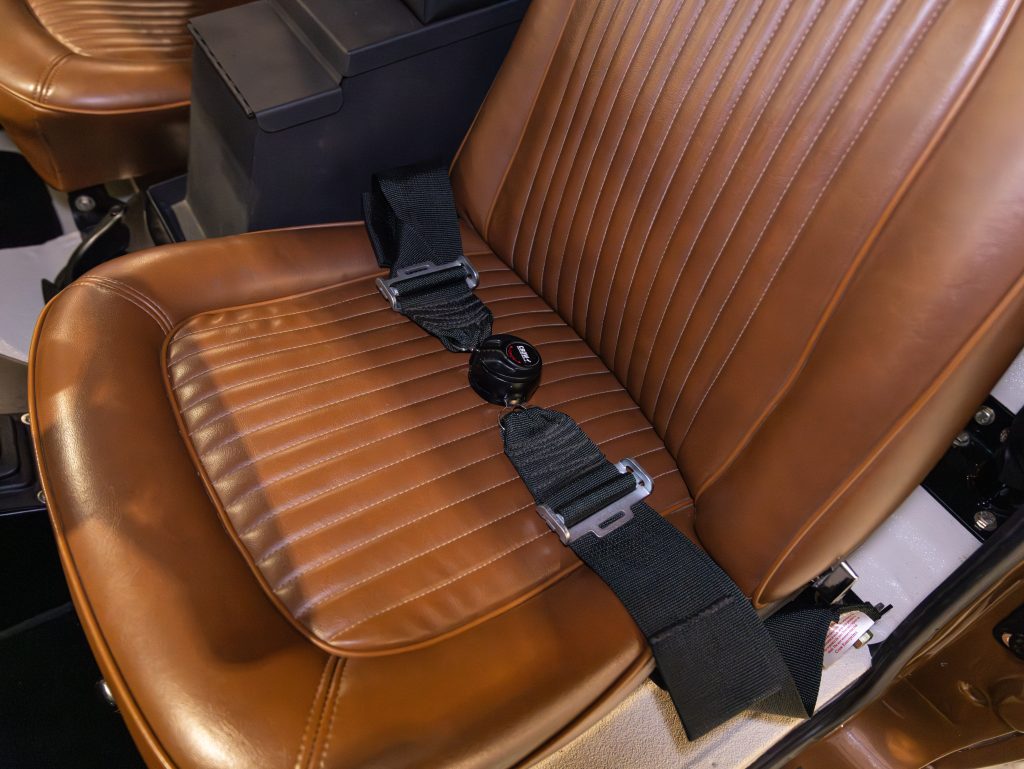 Vintage car interior with a brown leather seat and a seatbelt. - Monarch Showroom