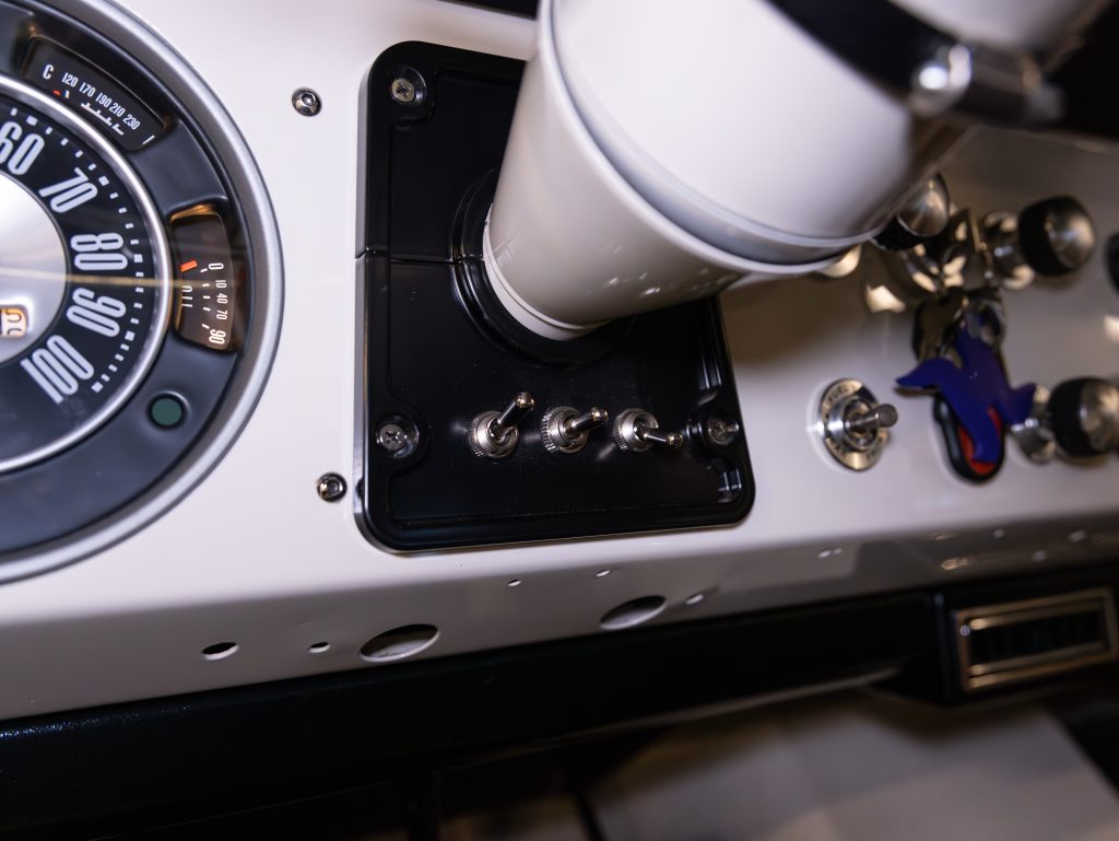 A close-up view of a vehicle's interior showing a gear stick, part of a dashboard with speedometer, and a cup in a cup holder. - Monarch Showroom