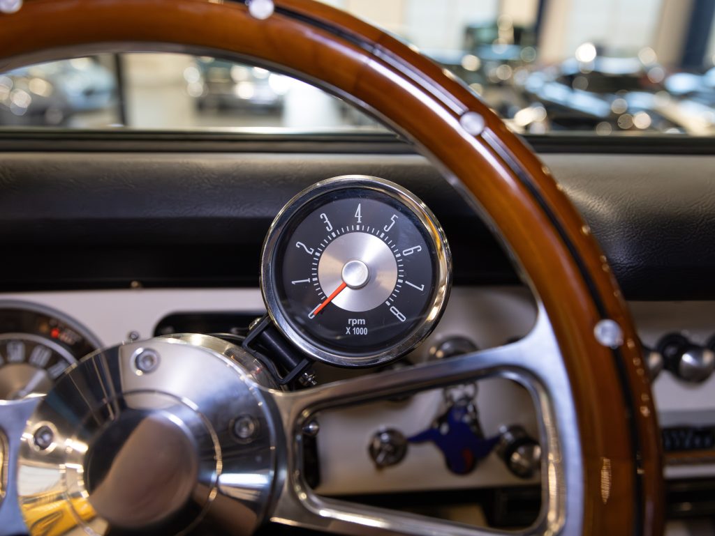 Close-up view of a car's tachometer and steering wheel with a blurred background of vehicle interiors. - Monarch Showroom