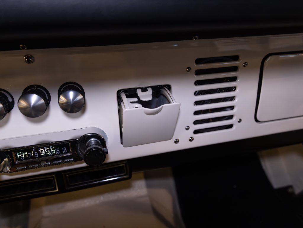 Dashboard of a vehicle with an open ashtray, temperature controls, and vents. - Monarch Showroom