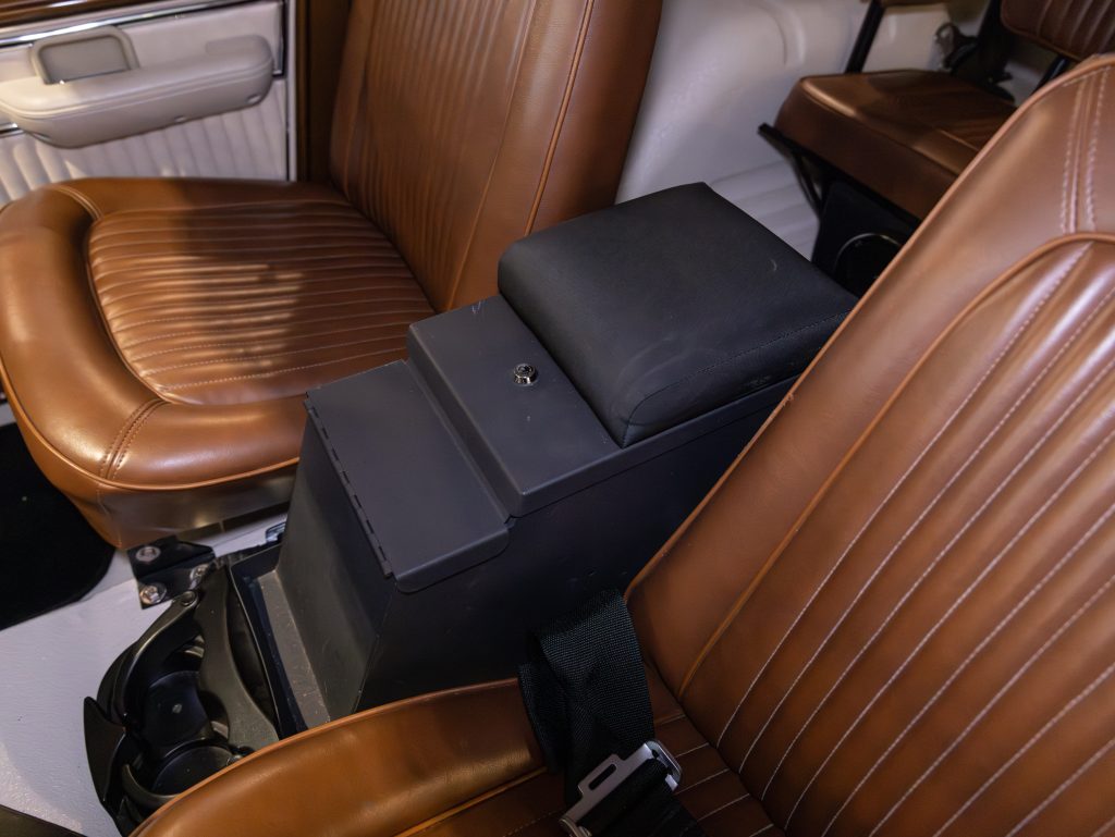 Interior of a vehicle showing brown leather seats with a black center armrest console. - Monarch Showroom