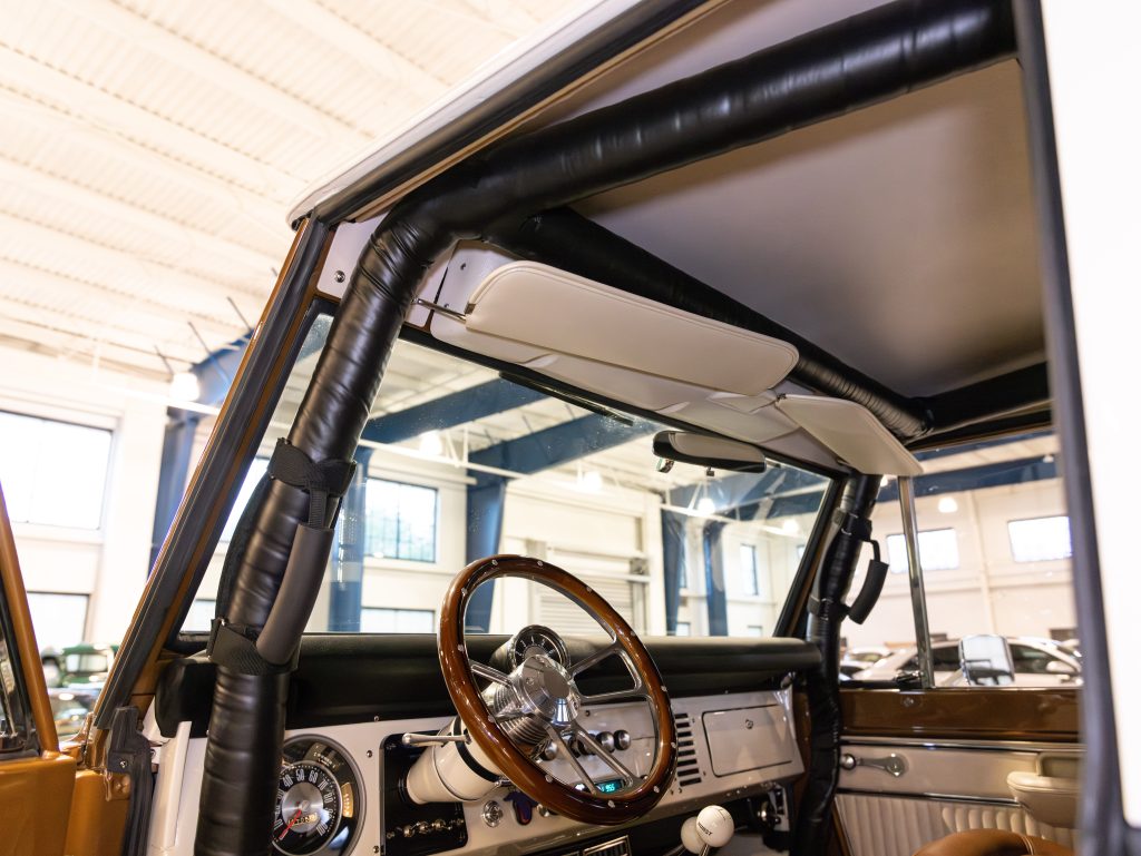 Interior view of a classic car showing the steering wheel, dashboard, and part of the convertible top mechanism. - Monarch Showroom