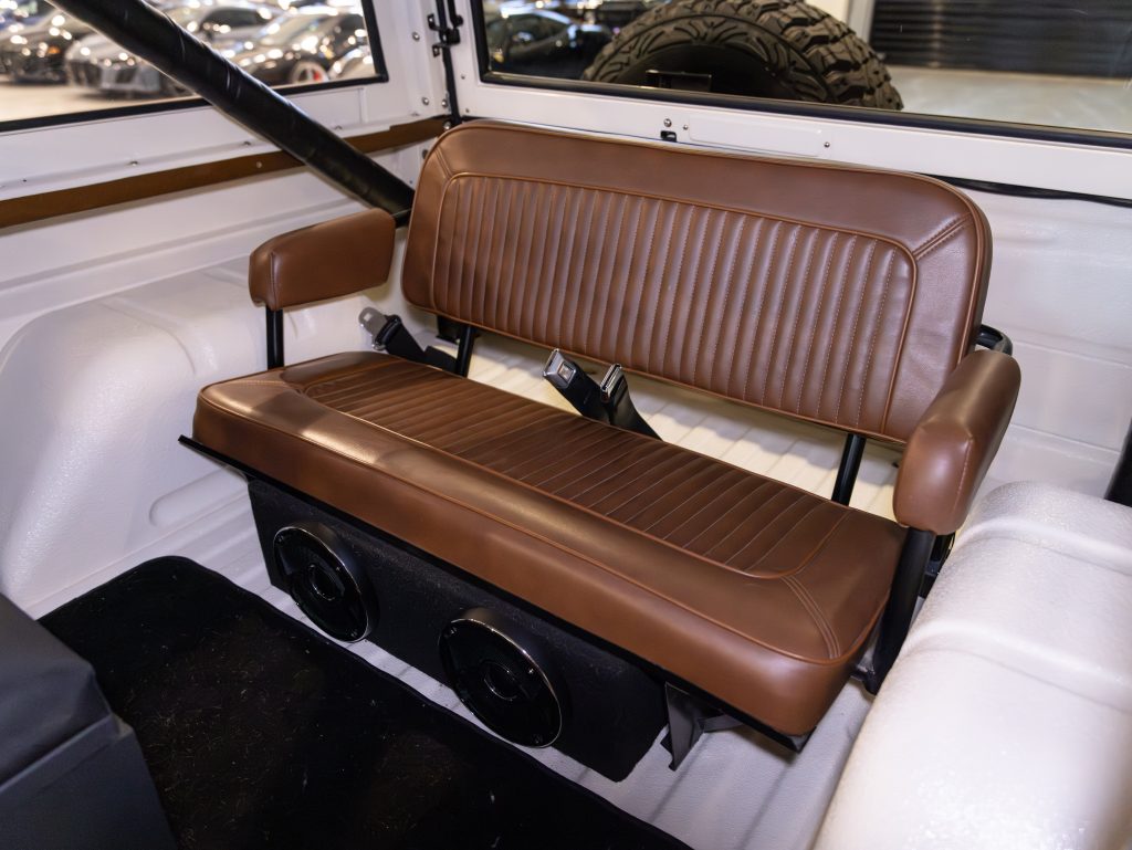 Brown leather bench seat with speakers mounted below, inside a classic vehicle cabin. - Monarch Showroom