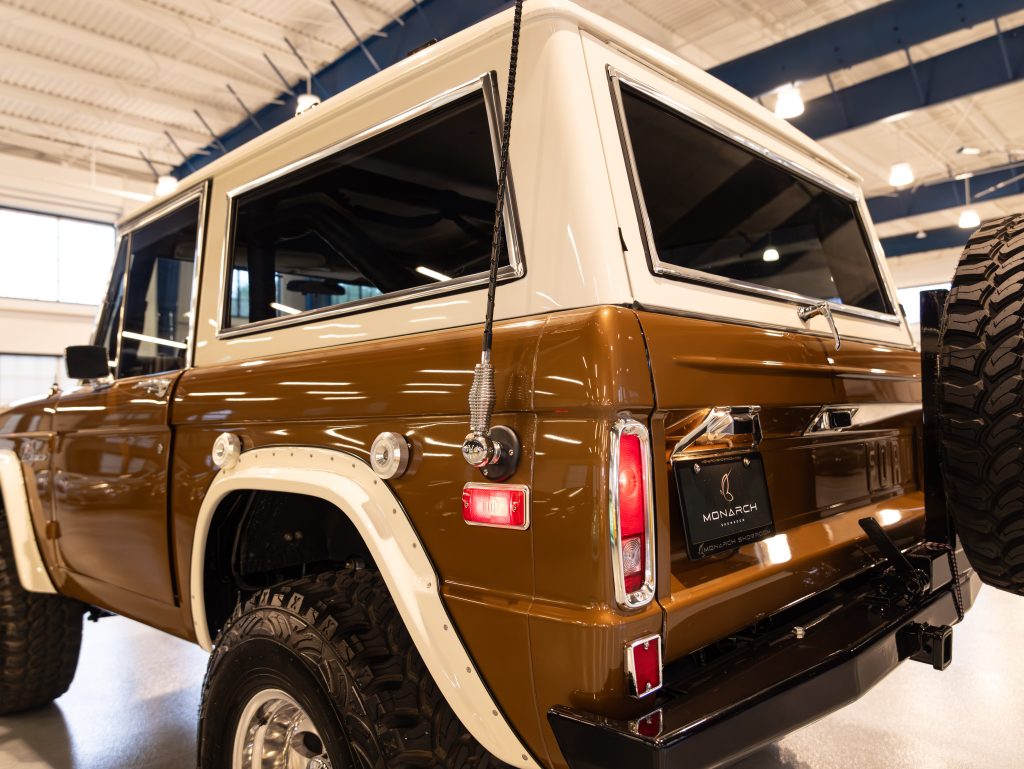 Rear view of a two-tone brown and white suv in a showroom setting. - Monarch Showroom
