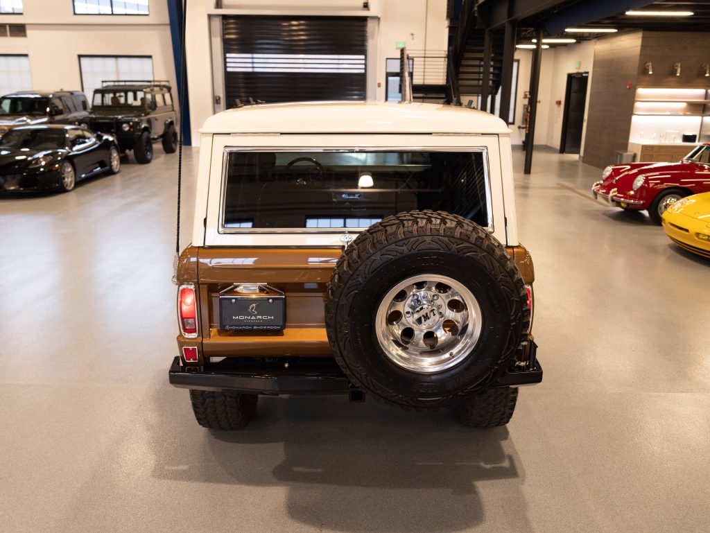 Rear view of a classic suv with a spare wheel mounted on the back, parked inside a showroom with other vehicles. - Monarch Showroom