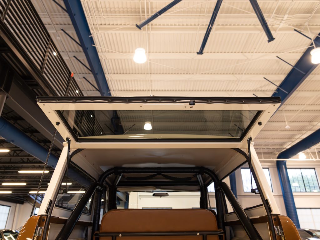 View of a vehicle's open sunroof from the inside, showing the interior ceiling and lighting of a building. - Monarch Showroom