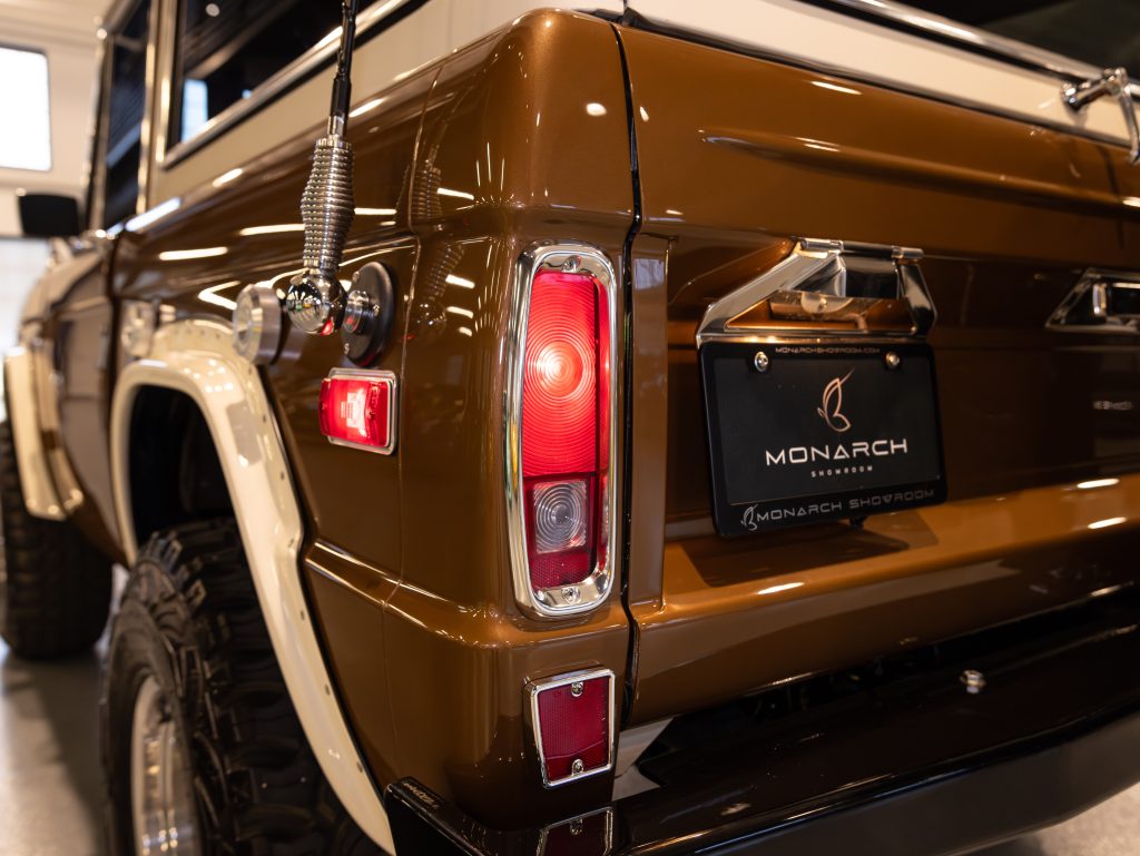 Close-up view of a vintage brown vehicle's rear taillight and badge, with a cb antenna visible. - Monarch Showroom