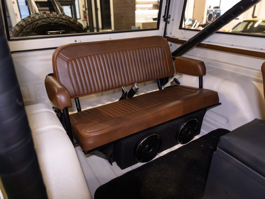 Rear bench seat with brown upholstery and speaker system in a vehicle interior. - Monarch Showroom