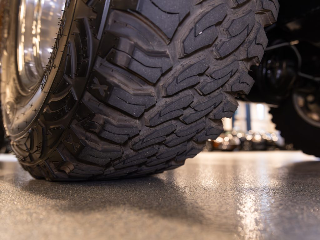 Close-up of a vehicle's tire tread on a shiny garage floor. - Monarch Showroom