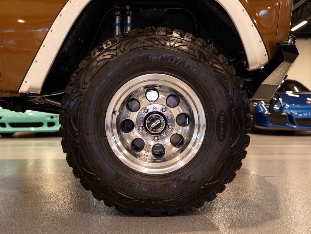 Close-up view of a polished alloy wheel with off-road tire on a vehicle in a garage setting. - Monarch Showroom
