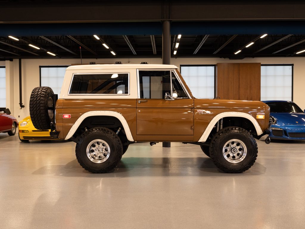 Vintage brown and white suv displayed in a showroom with cars in the background. - Monarch Showroom