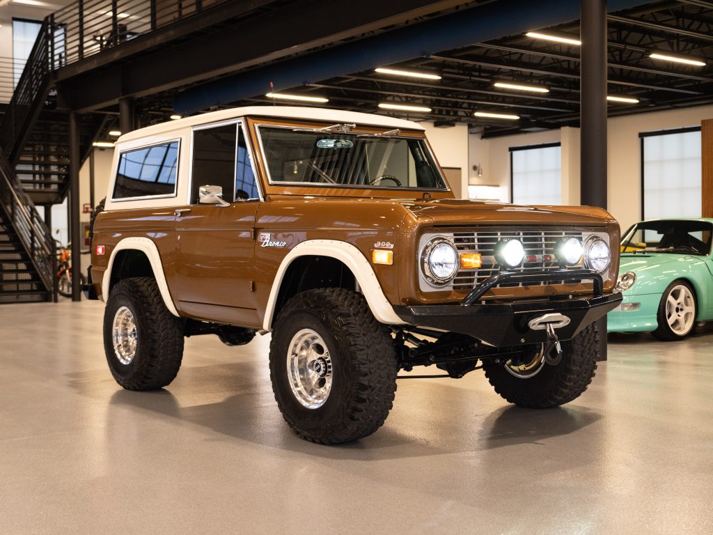 A vintage brown ford bronco parked indoors, featuring a lifted suspension and off-road tires. - Monarch Showroom