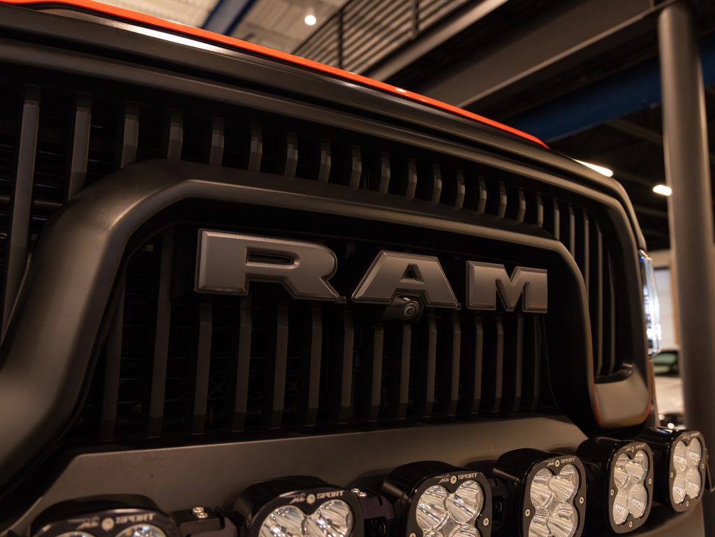 Close-up of a ram truck grille with auxiliary lights mounted below. - Monarch Showroom