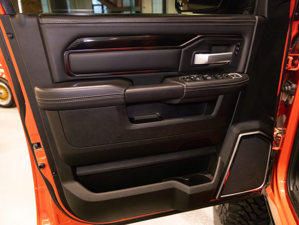 Interior door panel of a modern vehicle with control buttons and leather accents. - Monarch Showroom
