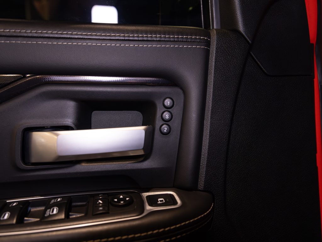 Interior close-up of a car door with control buttons for windows and mirrors. - Monarch Showroom