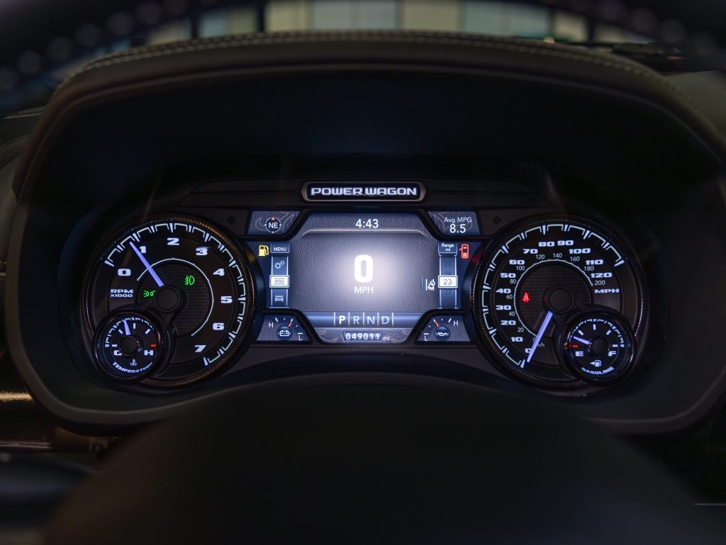 Digital dashboard of a vehicle displaying speedometer, tachometer, and other gauges during twilight hours. - Monarch Showroom