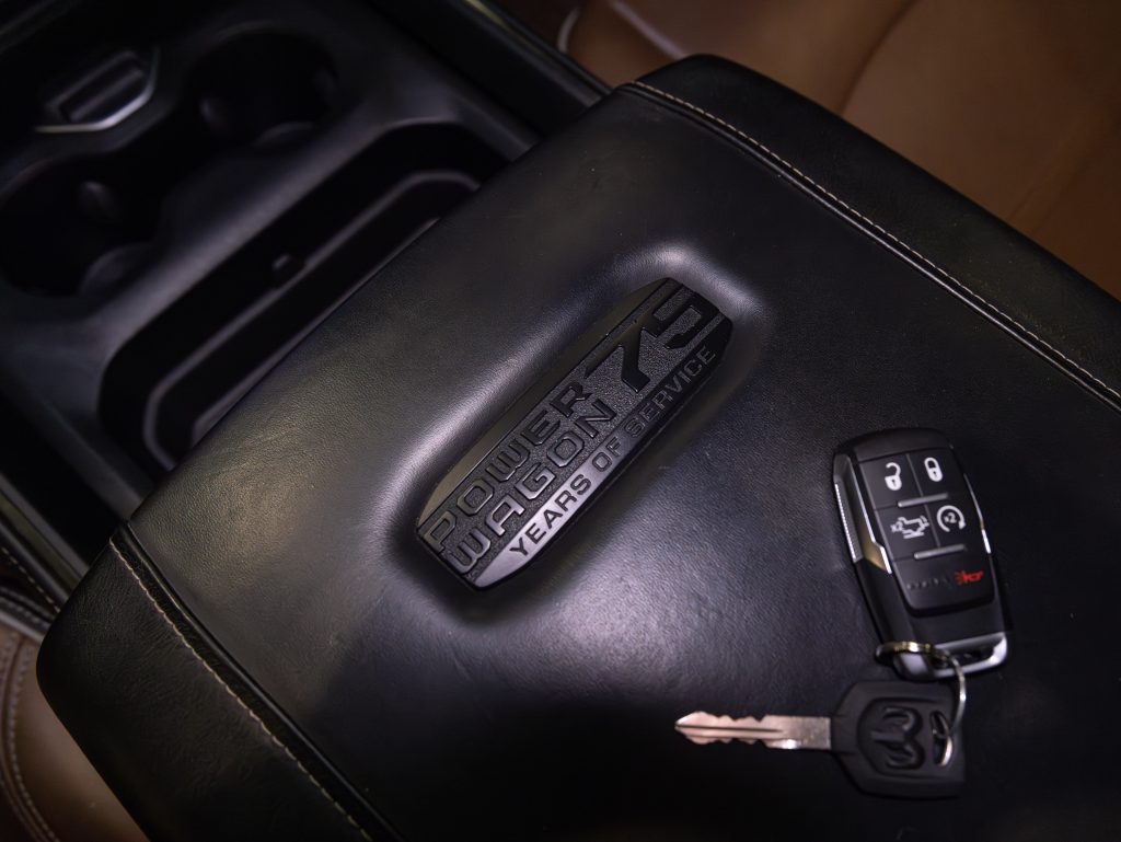 A car key fob rests on a black leather armrest with the embossed text "100 years of chevrolet. - Monarch Showroom