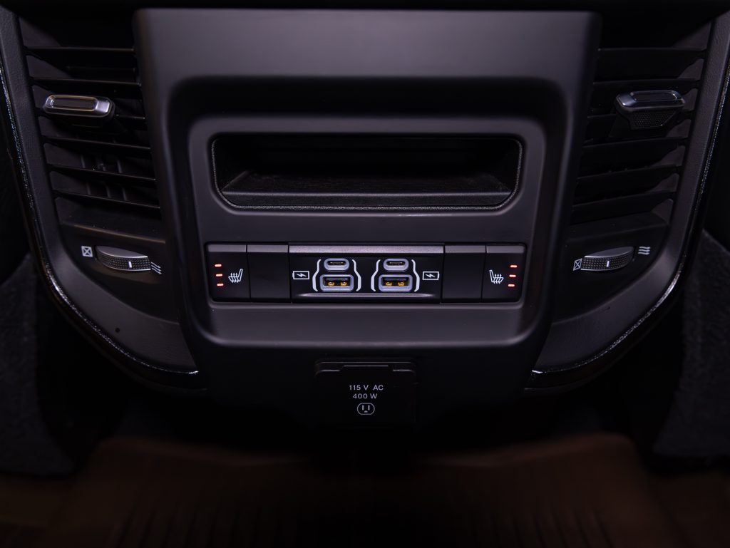 Car's rear center console featuring seat heater controls, usb ports, and a 115v ac power outlet. - Monarch Showroom